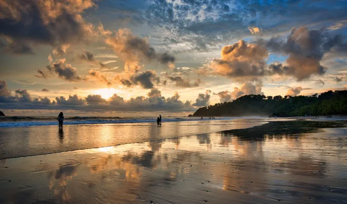 A serene Costa Rican beach at sunset, where vibrant reflections and a tranquil atmosphere are beautifully captured