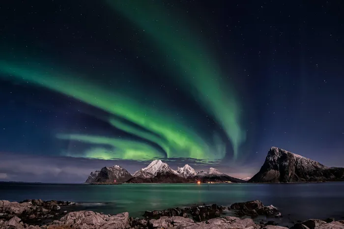 A breathtaking view of the Northern Lights over Sandnes, Norway's rugged mountains.