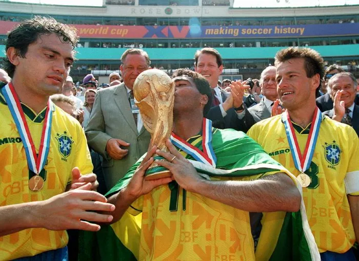 Brazilian forward Romario kisses the FIFA World Cup trophy in 1994 as his teammates Branco, left, and Dunga look on. Photo: AFP