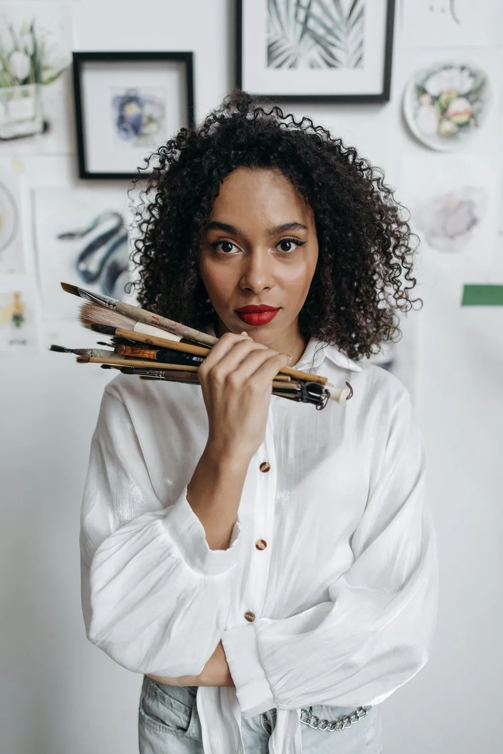 Woman wearing a white shirt holding paint brushes