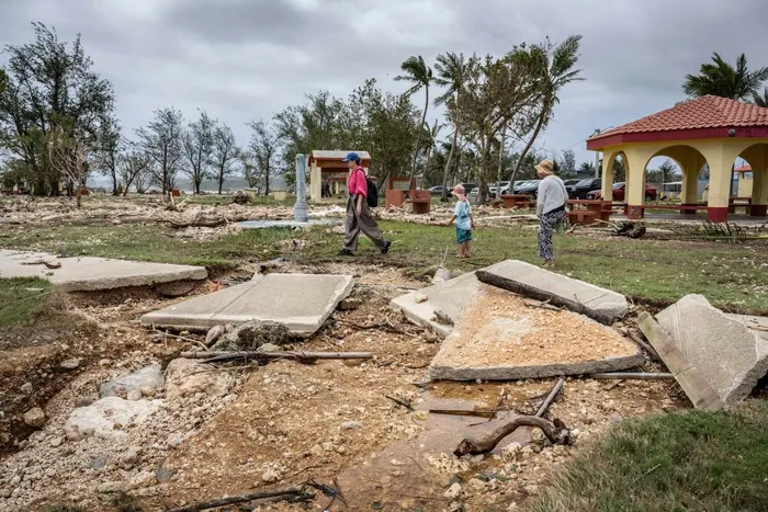 People walk past a damaged walkway at a park in the aftermath of Super Typhoon Bavi in Guam on July 7, 2026. 