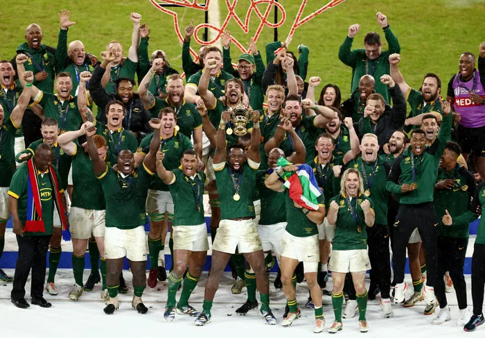 The team celebrate with arms raised as the captain holds the trophy aloft.