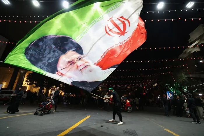 A man waves a flag near Imam Reza's shrine as mourners arrive for the funeral of slain Iranian leader Ali Khamenei and members of his family in Mashhad early on July 9, 2026.
Iranians were preparing on July 9 to bury their slain leader Ali Khamenei in his hometown of Mashhad in northeast Iran, as new US strikes threatened to trigger a fresh escalation in the Middle East war. The late supreme leader's burial follows a multi-day funeral ceremony that attracted millions of mourners across various cities in both Iran and Iraq.