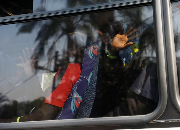Malawian immigrants wave from a bus heading to Malawi.