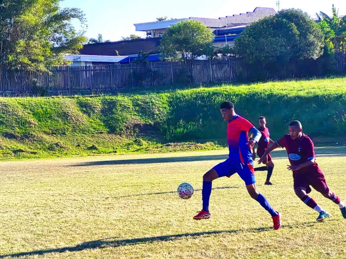 Montford Crusaders’ Aseza Mthinsto (blue and red) drives the ball forward under pressure from Arena Spurs’ Mshishi Francis (maroon) in a high-intensity moment, 
