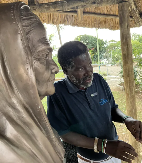 Bongani Mthembu, curator of the Gandhi Settlement in Bhambayi, next to a bust of Kasturba Gandhi just outside her historic home.