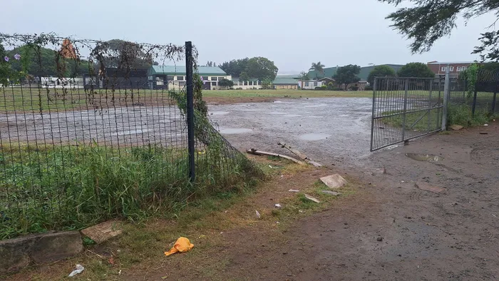 Broken fencing and hazardous conditions surround the school field.