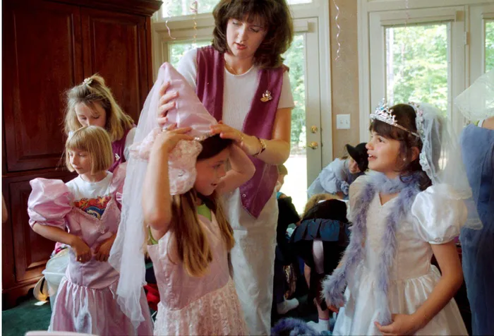 Sisters-in-law Joy and Dawn Yates, the creators of Little Princess Tea Parties, help guests dress up for a 7-year-old’s birthday party in Woodbridge, Virginia, in 1999. 