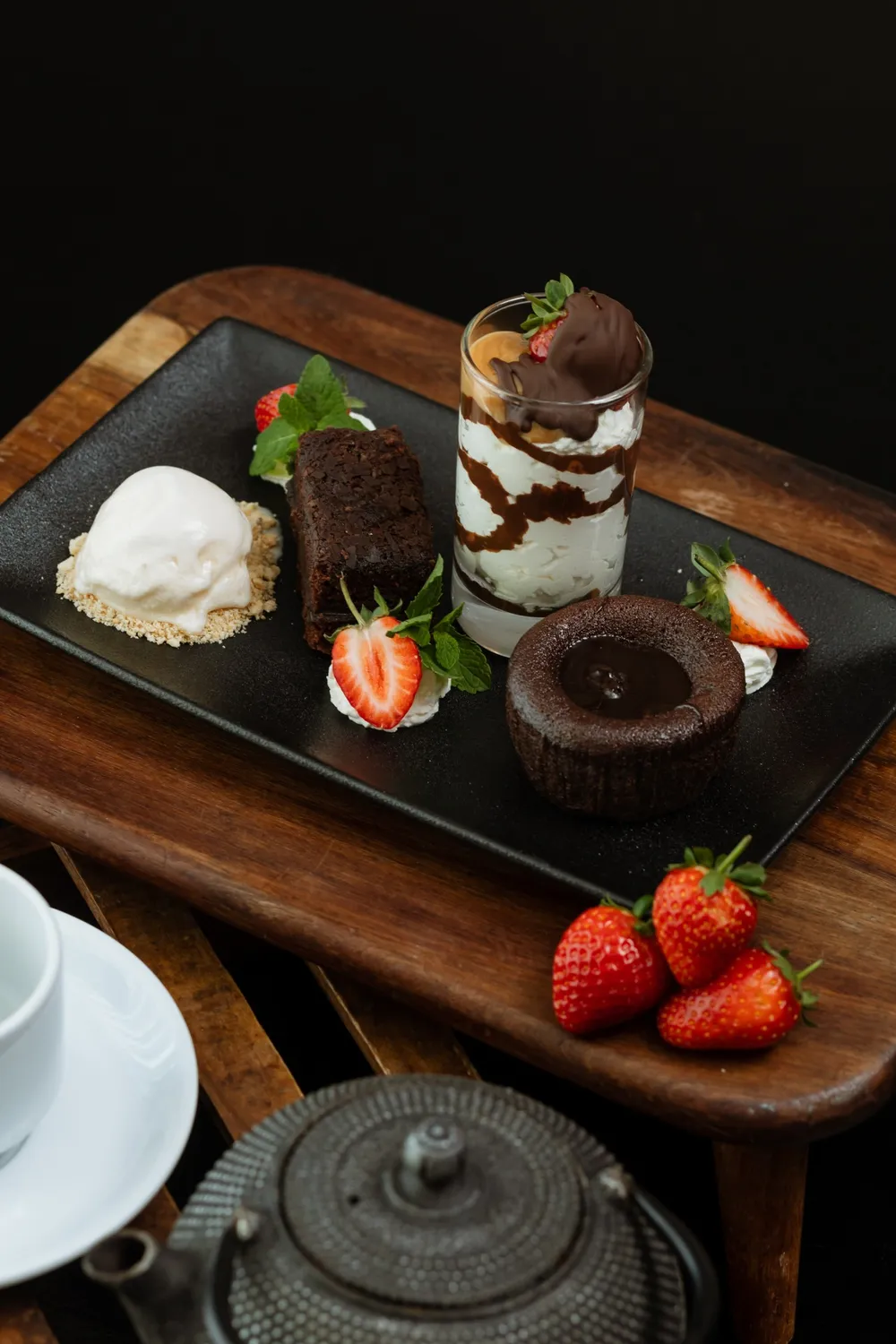 Dessert featuring chocolate fondant, chocolate volcano, chocolate velvet and white chocolate served with ice cream on a black plate. 