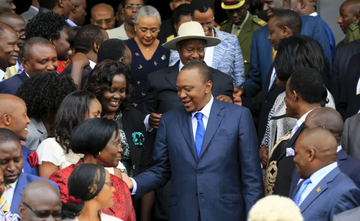 Kenyan President Uhuru Kenyatta (centre) is accompanied by his Ugandan counterpart Yoweri Museveni (wearing a hat) as he meets Ugandan legislators outside the parliament building in the capital Kampala on August 10, 2015. Picture: James Akena