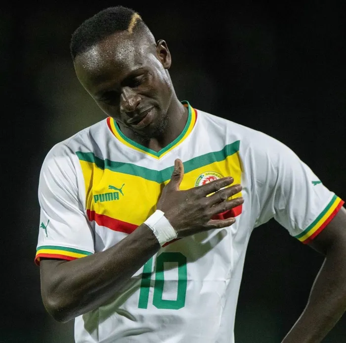 a Senegal football player looks down while putting his hand on his chest