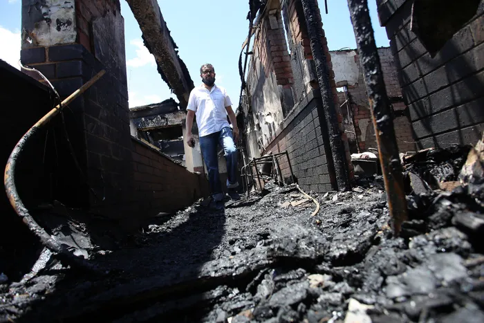 Community Activist Dees Ahmed walks through fire debris at Povall Court. Picture: Sibusiso Ndlovu/African News Agency(ANA)