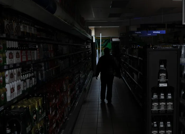 A Security guard walks down a dark isle in a PnP liquor store in Durbanville. File Picture: Henk Kruger/African News Agency (ANA)