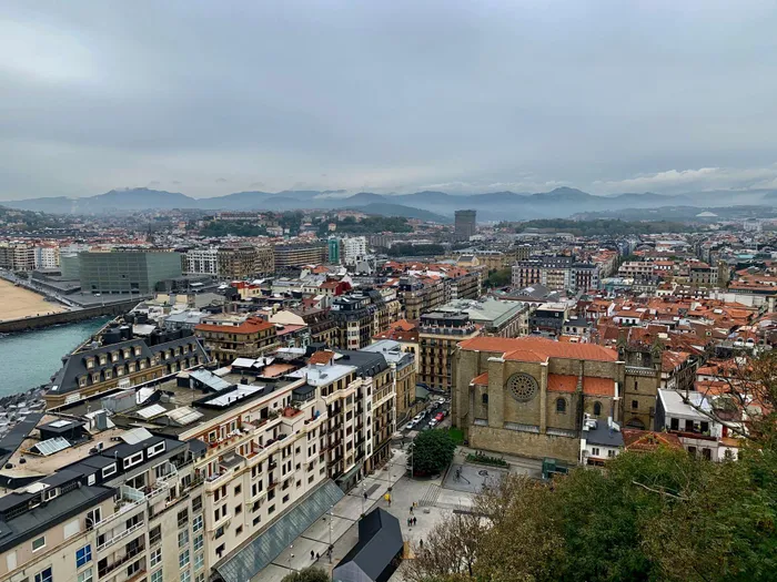 
A bird's-eye view of San Sebastián, Spain, showing mountains under overcast skies.

