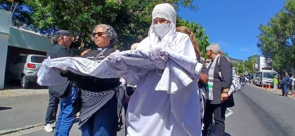 ANSEHEN: Demonstranten in Kapstadt tragen Leichentuch mit den Namen von 22 ...
