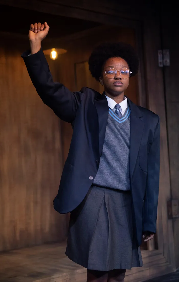 Actor Zilungile Mbombo portraying student leader Kedibone Moloi, standing defiantly in a school uniform with a raised fist.
