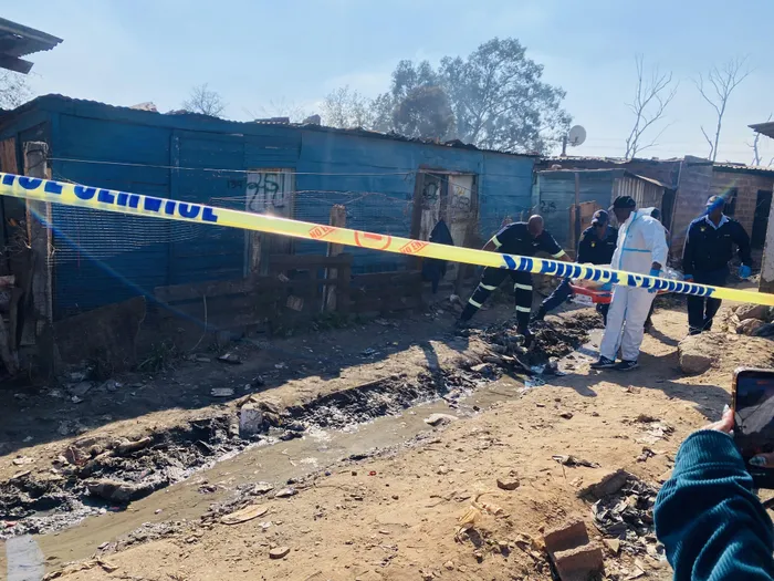 Police officers secure the crime scene at the Jumpers informal settlement in Cleveland, Johannesburg, after a mass shooting left 12 people dead and several others wounded.