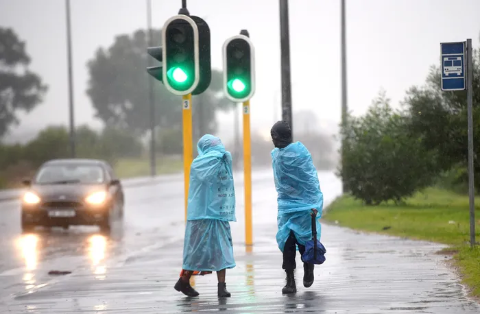Mfuleni residents walk along flooded Hindle Road.