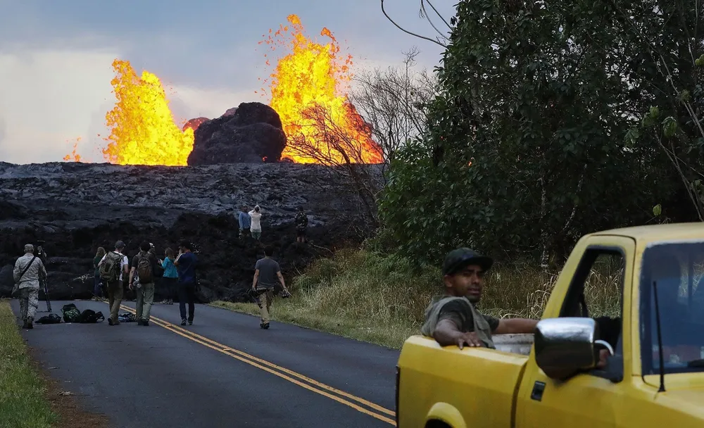 Onlookers and media workers gather as lava from a Kilauea volcano fissure erupts in Leilani Estates, on Hawaii's Big Island, on May 26, 2018, in Pahoa, Hawaii.  Picture:  Mario Tama/Getty Images/AFP