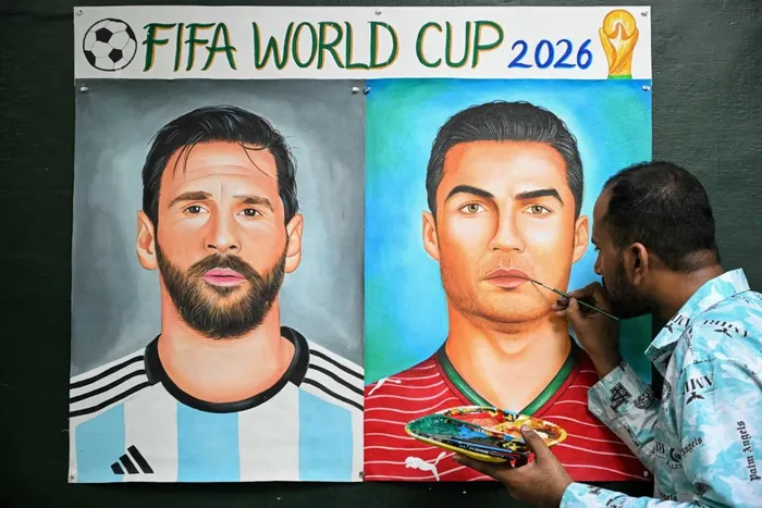 An artist adds final touches to a painting featuring football players Argentina's Lionel Messi and Portugal's Cristiano Ronaldo in Amritsar at the 2026 Fifa World Cup tournament. 
