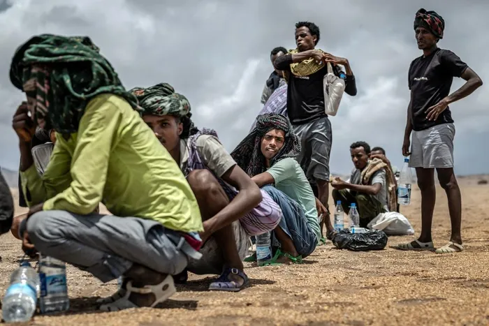 Ethiopian migrants take a break to hydrate and eat after receiving assistance from the International Organization for Migration (IOM) in a remote desert area under high temperatures during their journey along the so-called Eastern Route as they return from Yemen, near Obock