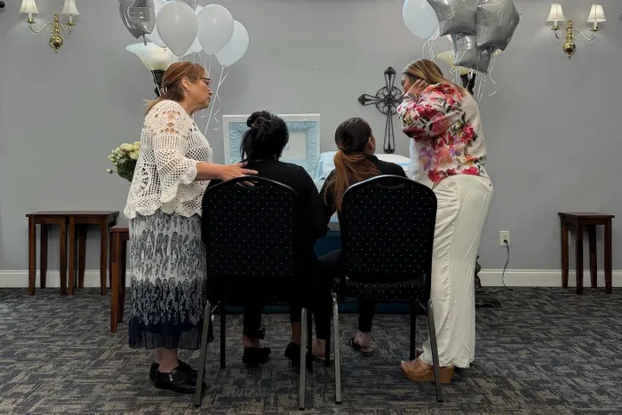 Friends support Orlin's mother and her sister, seated, who were allowed to return to the US for his funeral.