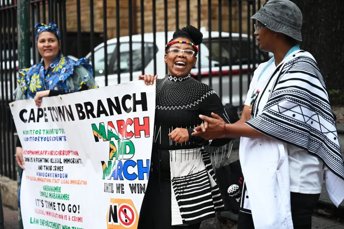 Members of March and March, some dressed in traditional attire, carry the organisation's banner as they lead the anti-undocumented migrant protest through Long Street in Cape Town on Thursday.