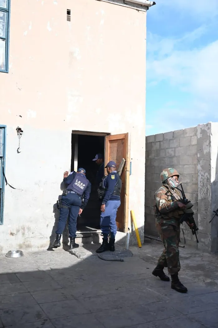 Police officers stop at a home in Tafelsig during Wednesday’s Operation Prosper walkabout and oversight visit to the Cape Flats.