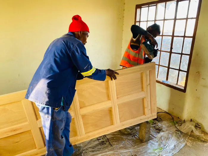 Workers install a door in one of the houses 