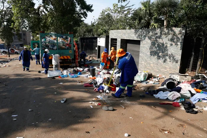 Municipal workers begin the cleanup process at Sherwood Hall, collecting discarded items left behind.