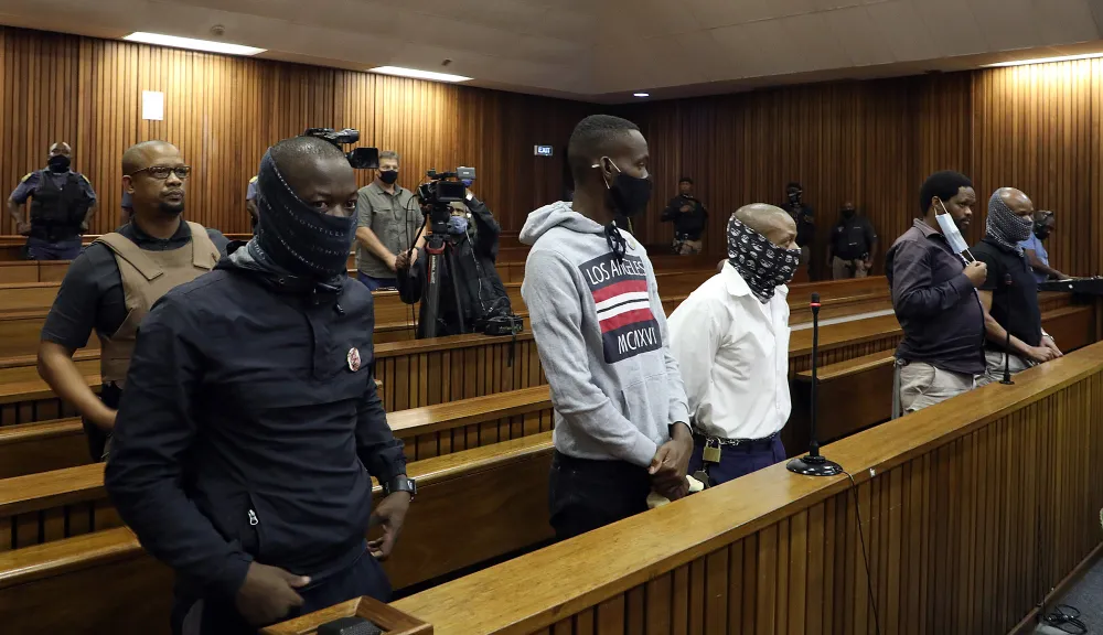 Five men standing in the dock with armed guards behind them 