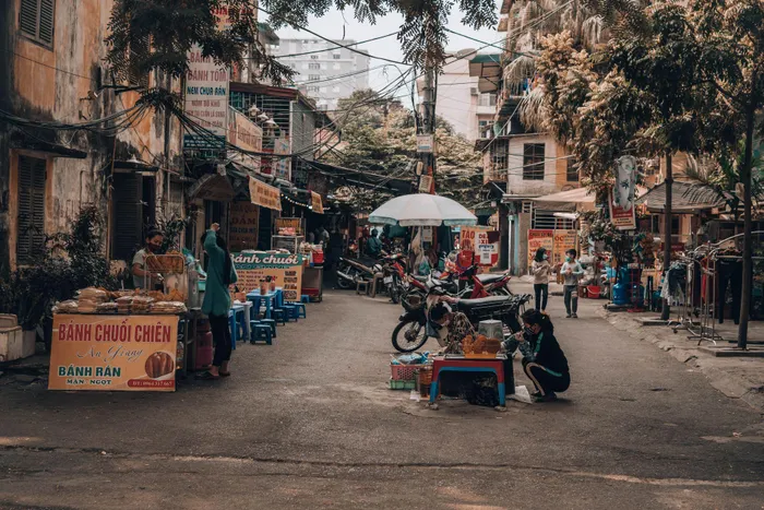 Vietnamese street food market, bustling with people shopping at various food stalls.