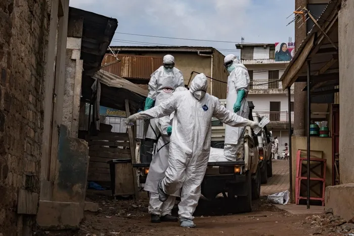 A Uganda Red Cross Society worker in protective gear are sprayed with disinfectant during the evacuation of the body of a suspected Ebola victim