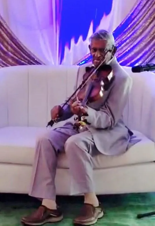 Dennis Naidu playing the violin at his 100th birthday party