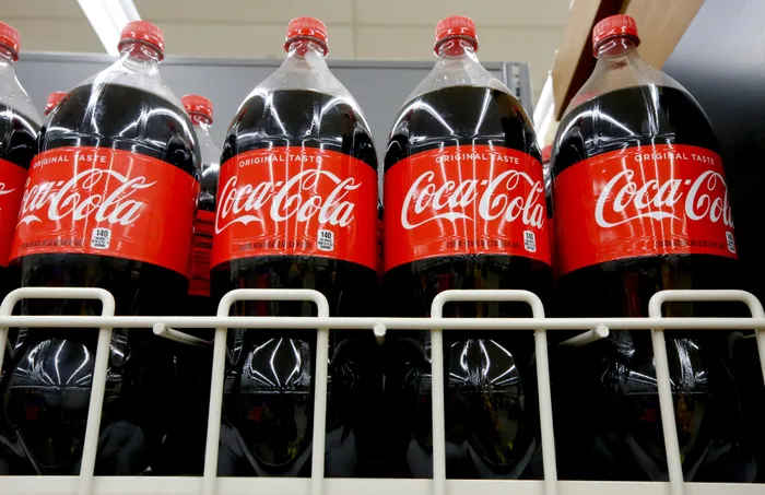 FILE- In this Aug. 8, 2018, file photo bottles of Coca-Cola sit on a shelf in a market in Pittsburgh. Coca-Cola is taking a minority stake in Iris Nova, the company behind a cashierless New York store where customers pay for drinks via text message. (AP Photo/Gene J. Puskar, File)