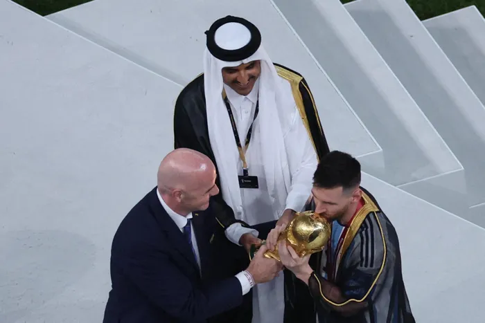 Argentina's forward #10 Lionel Messi kisses the World Cup trophy as FIFA President Gianni Infantino and Qatar's Emir Sheikh Tamim bin Hamad al-Thani look on during the Qatar 2022 World Cup trophy ceremony after the football final match between Argentina and France at Lusail Stadium in Lusail, north of Doha on December 18, 2022.