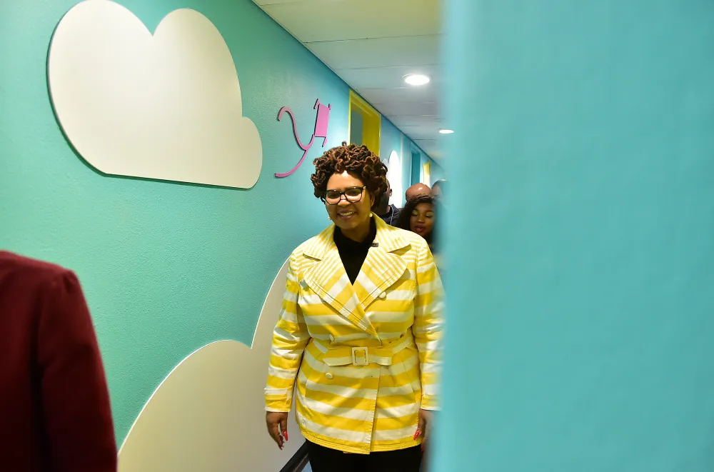 A woman walking next to a green wall