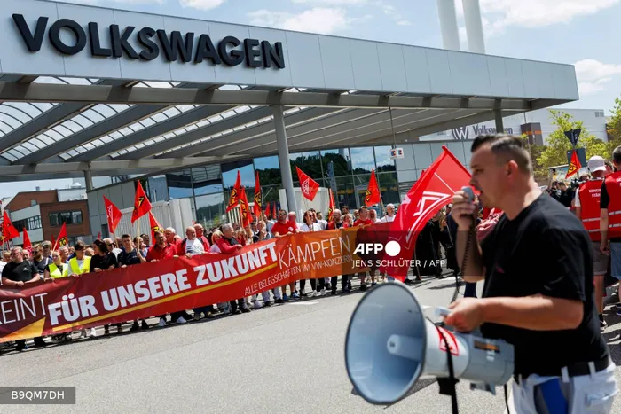 A participant with a megaphone addresses employees of German car maker Volkswagen (VW) during a rally called by German trade union IG Metall to protest against restructuring and mass job cut plans at the VW plant in Zwickau, eastern Germany on July 9, 2026.