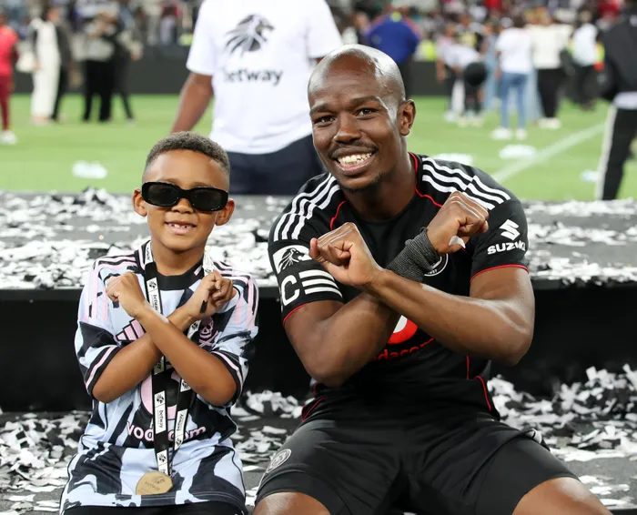 Nkosinathi Sibisi, captain of Orlando Pirates, celebrates with a young buck after winning the Betway Premiership title after beating Orbit College at Mbombela Stadium on Saturday. 
