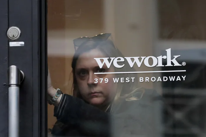 FILE PHOTO: A woman exits a WeWork co-working space in New York. Listing of fashionable shared workspace landlord will give JP Morgan bragging rights and hefty chunk of fees