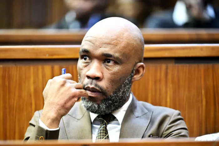 Vusimuzi 'Cat' Matlala, pen in hand, follows proceedings from the dock of the Johannesburg High Court, where he and four co-accused are on trial on 25 charges