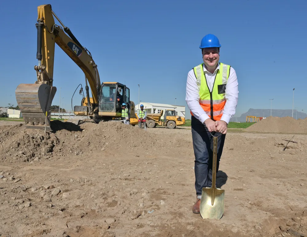 Man wearing hard hat in front of a digger.