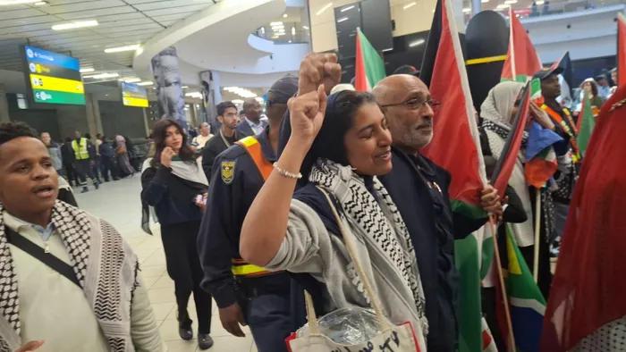 An emotional Hajar Kagiso Al Thaira Ahjum Mathee chants 'Free Palestine' at O.R. Tambo International Airport, embodying the spirit of resilience and solidarity after enduring harrowing experiences during the Gaza flotilla mission.