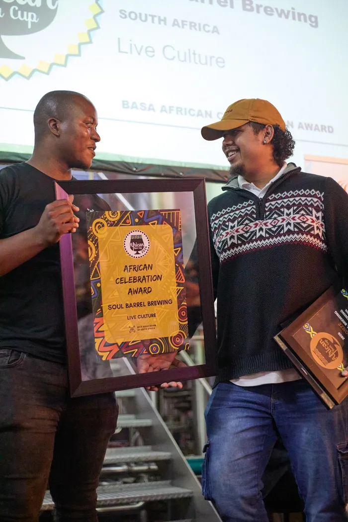 Archy Hlahla of BASA presents the African Celebration Award to Devin Hendricks of Soul Barrel Brewing.