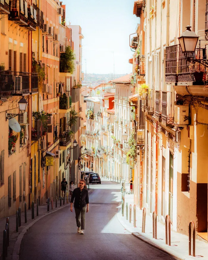 A sunlit street in Madrid offers a picturesque view, beautifully capturing the essence of the city's vibrant architecture.

