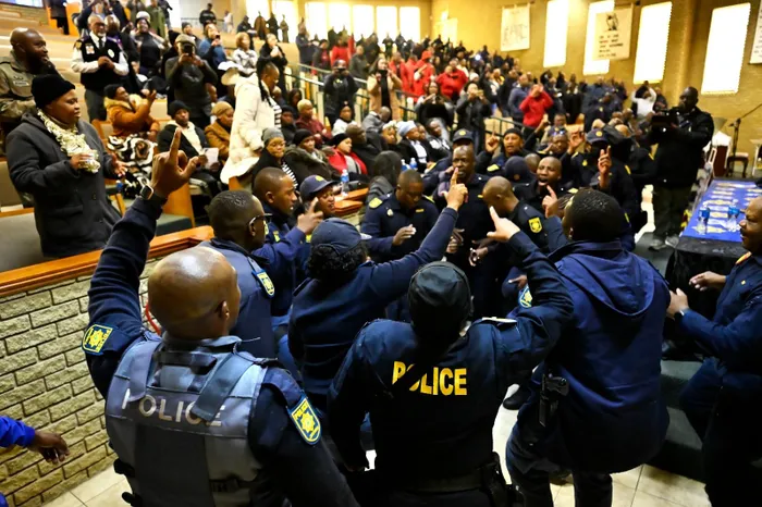 Police officers sing during the memorial service for the two slain officers in Westdene.