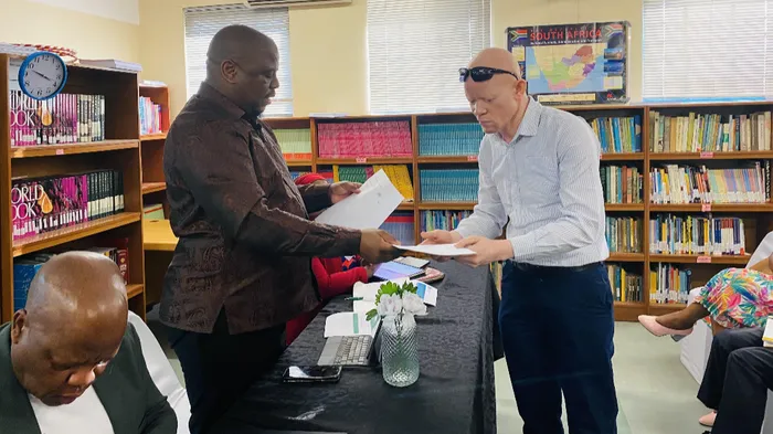 KwaZulu-Natal Education MEC Sipho Hlomuka receiving a memorandum of grievances by parents from the member of the school governing body, Bulelani Majola, in uMkhumbane Secondary School, Chesterville, that has been plagued by academic disruption due to a teacher boycott by members of the South African Democratic Teachers Union. 