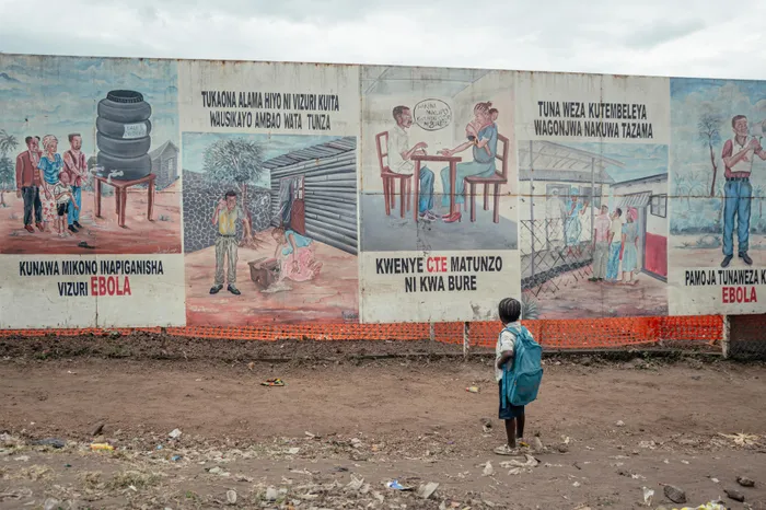 A child returning from school stops to look at Ebola awareness illustrations displayed on the signboards of the Ebola Treatment Center in Munigi this week. The sole airport providing humanitarian organisations access to the epicentre of an Ebola outbreak in the Democratic Republic of Congo reopened on Tuesday when the reported number of suspected cases declined.