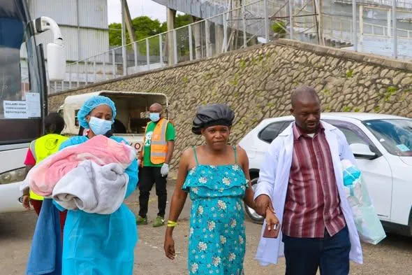 Estele Charles, a mother of one who had lived in South Africa for five years, flanked by health officials after her arrival in Malawi from South Africa through the government-led voluntary repatriation programme.