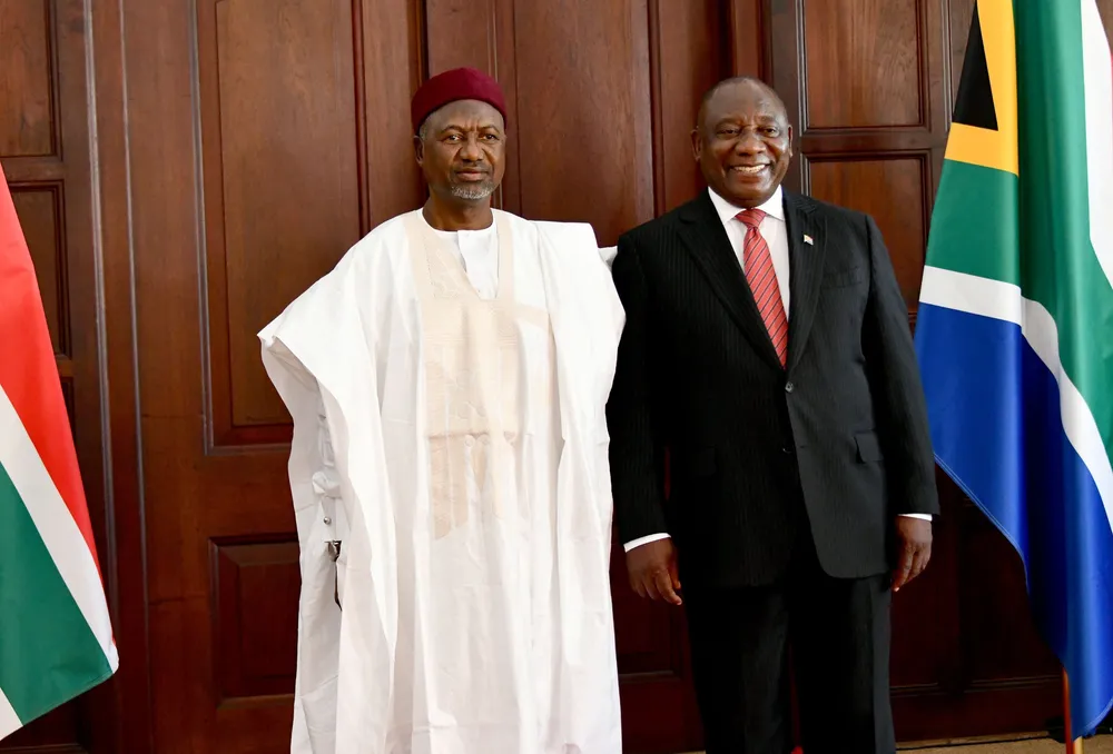 Two men, one in a black suit and the other in white African attire